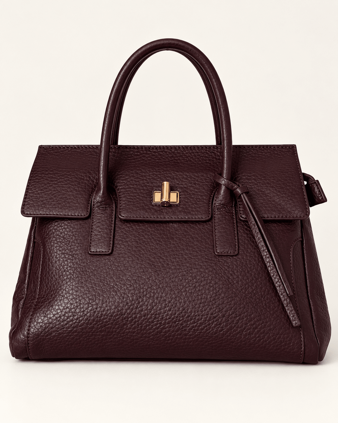 Mala Júlia bordeaux vista de frente, com pala, fecho dourado e tiras decorativas junto à alça.