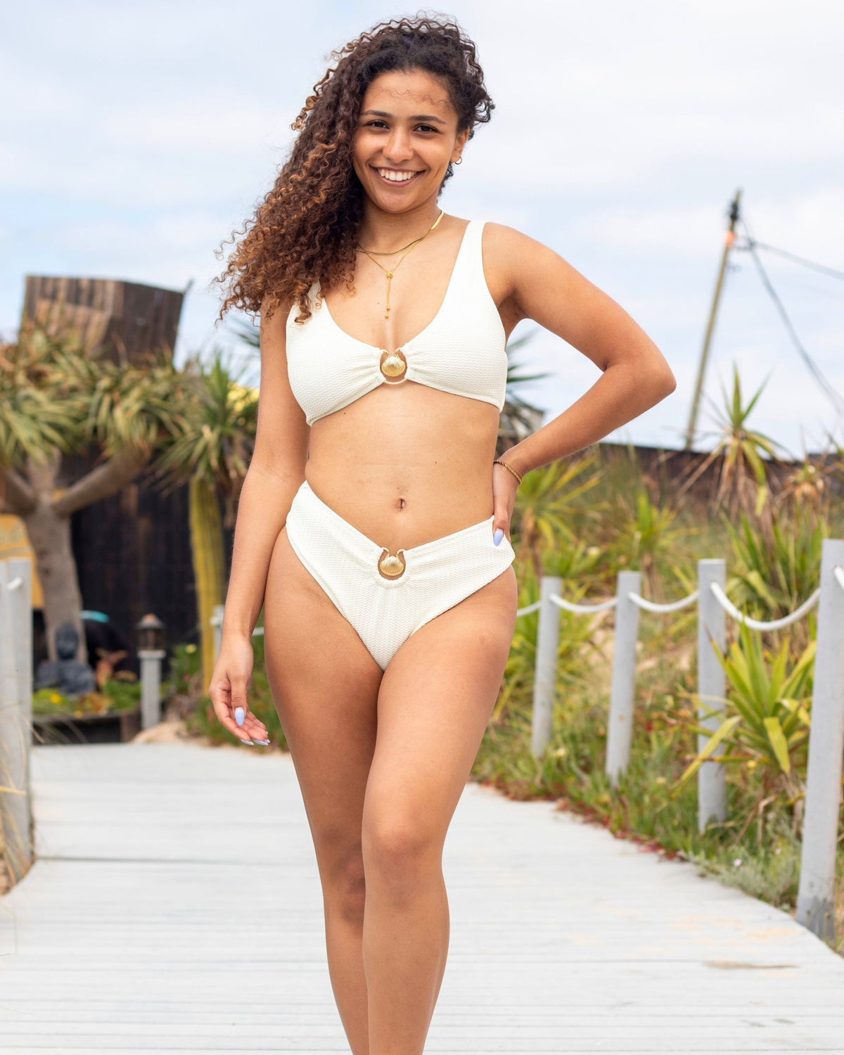 Biquíni branco com top triangular e cueca alta, detalhe dourado oval ao centro