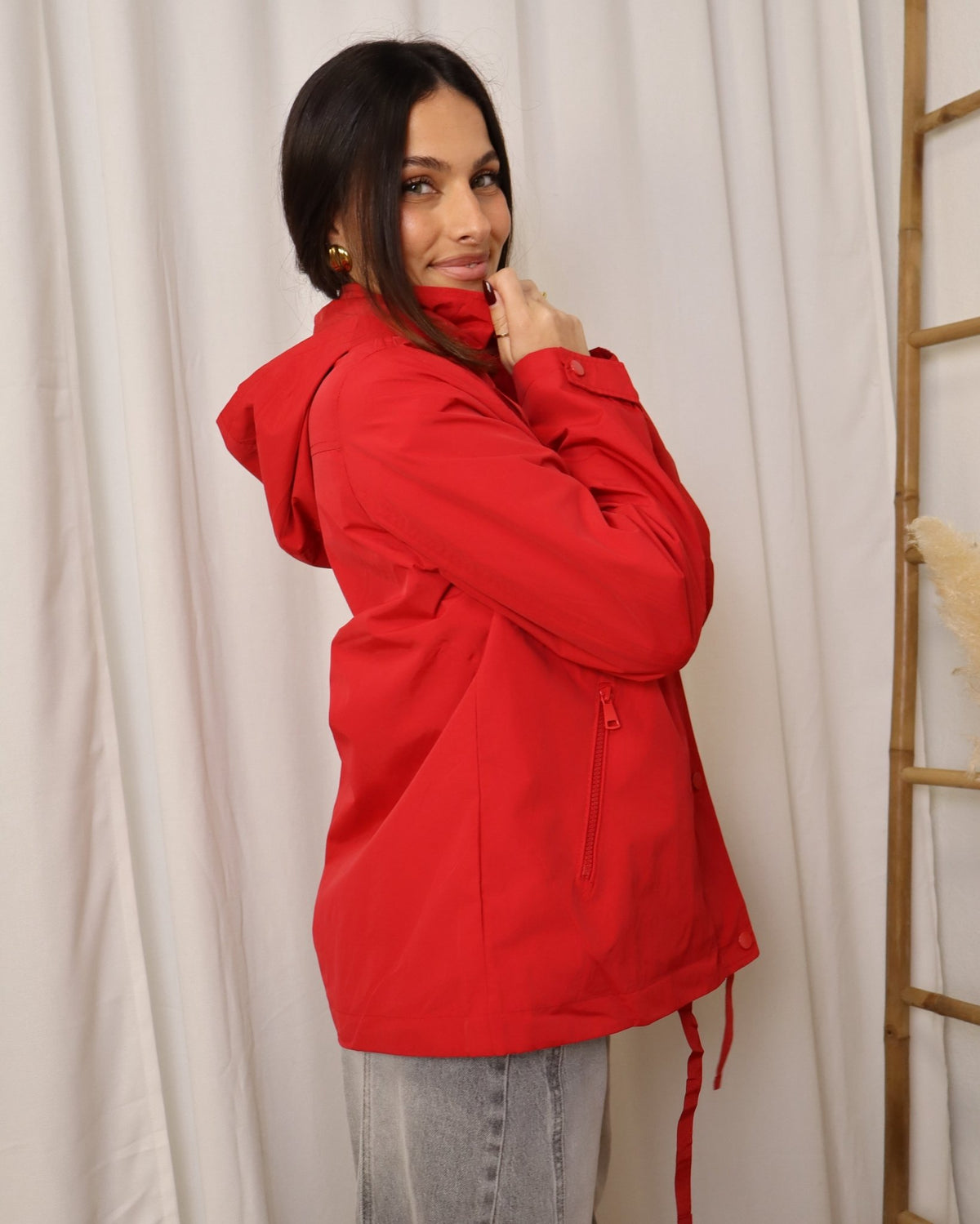 Parka vermelha com capuz, fecho de botões e cordão pendente na frente.