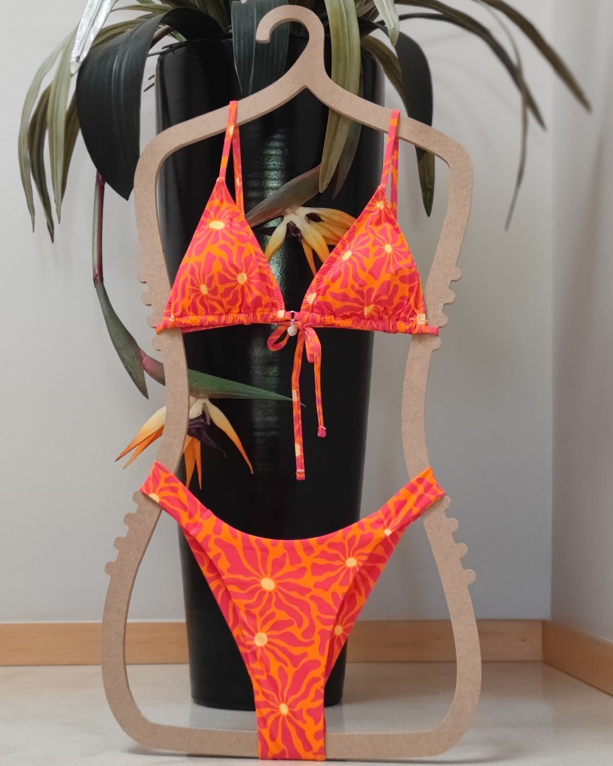 Parte de baixo de biquíni laranja floral com laço, pendurado num cabide