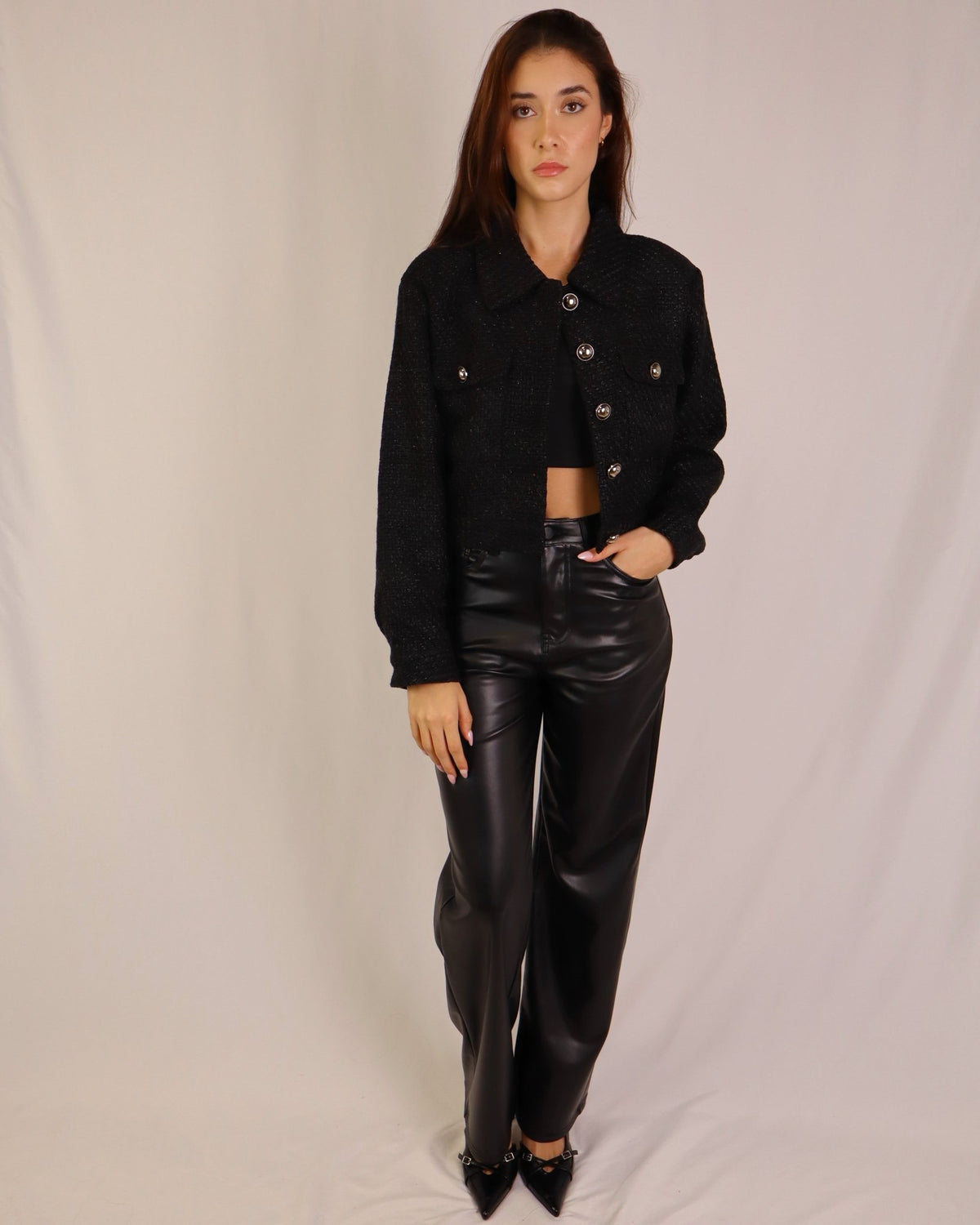 Calças estilo couro preto, cintura alta e pernas estreitas, bainha discreta