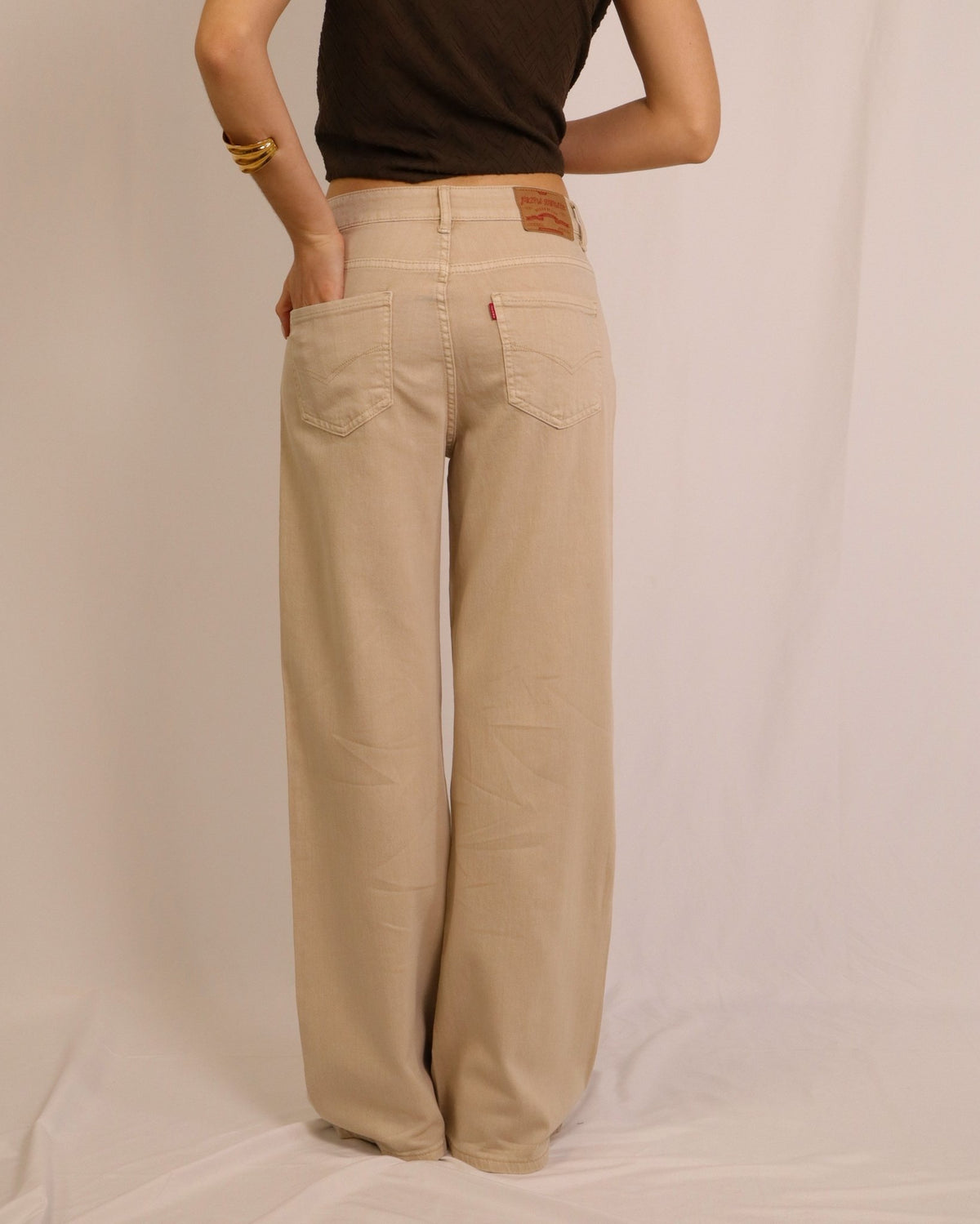 Calça wide leg bege, cintura com passadores e dois bolsos traseiros
