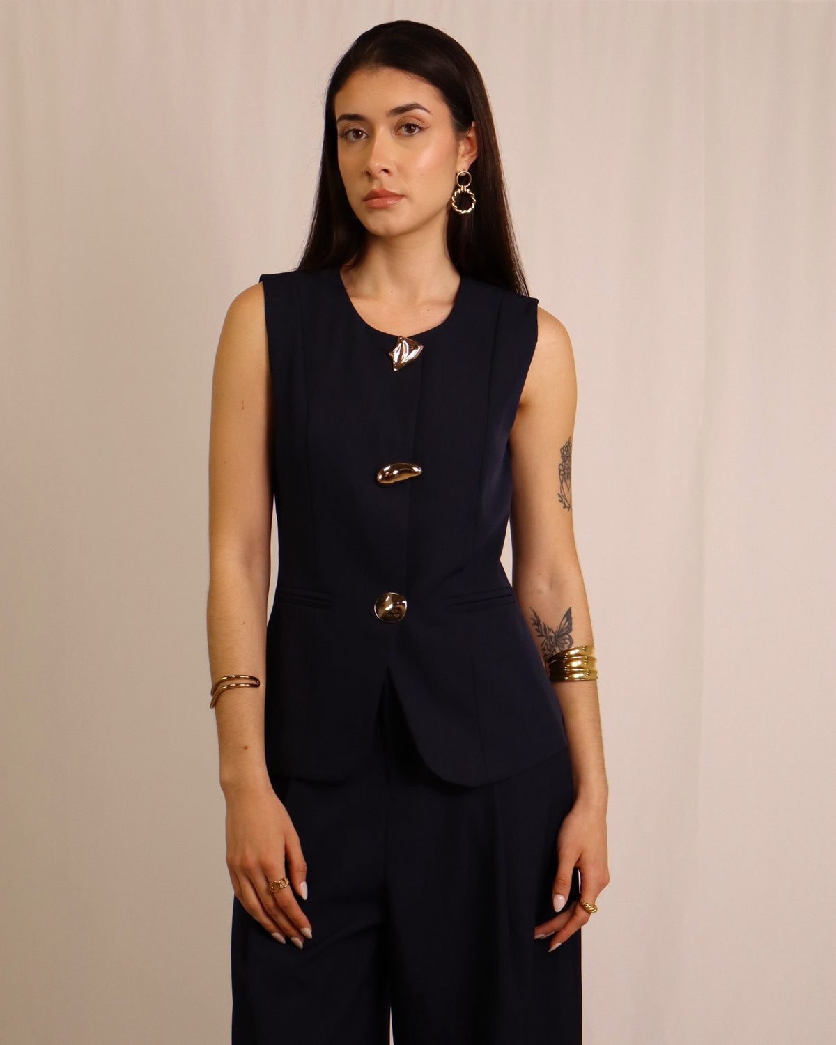 Conjunto feminino azul escuro com colete sem mangas e calças largas, botões e bolso.