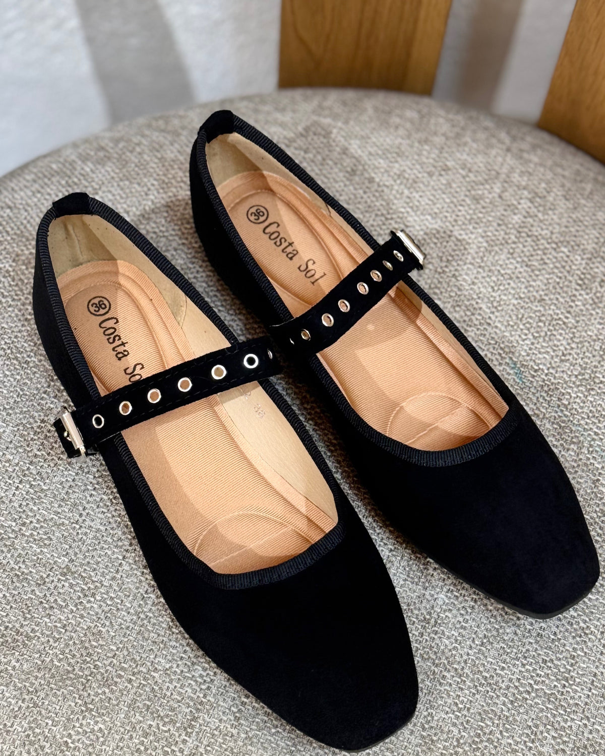 Sapatos pretos com tira larga e fivela metálica, detalhe de ilhós decorativos