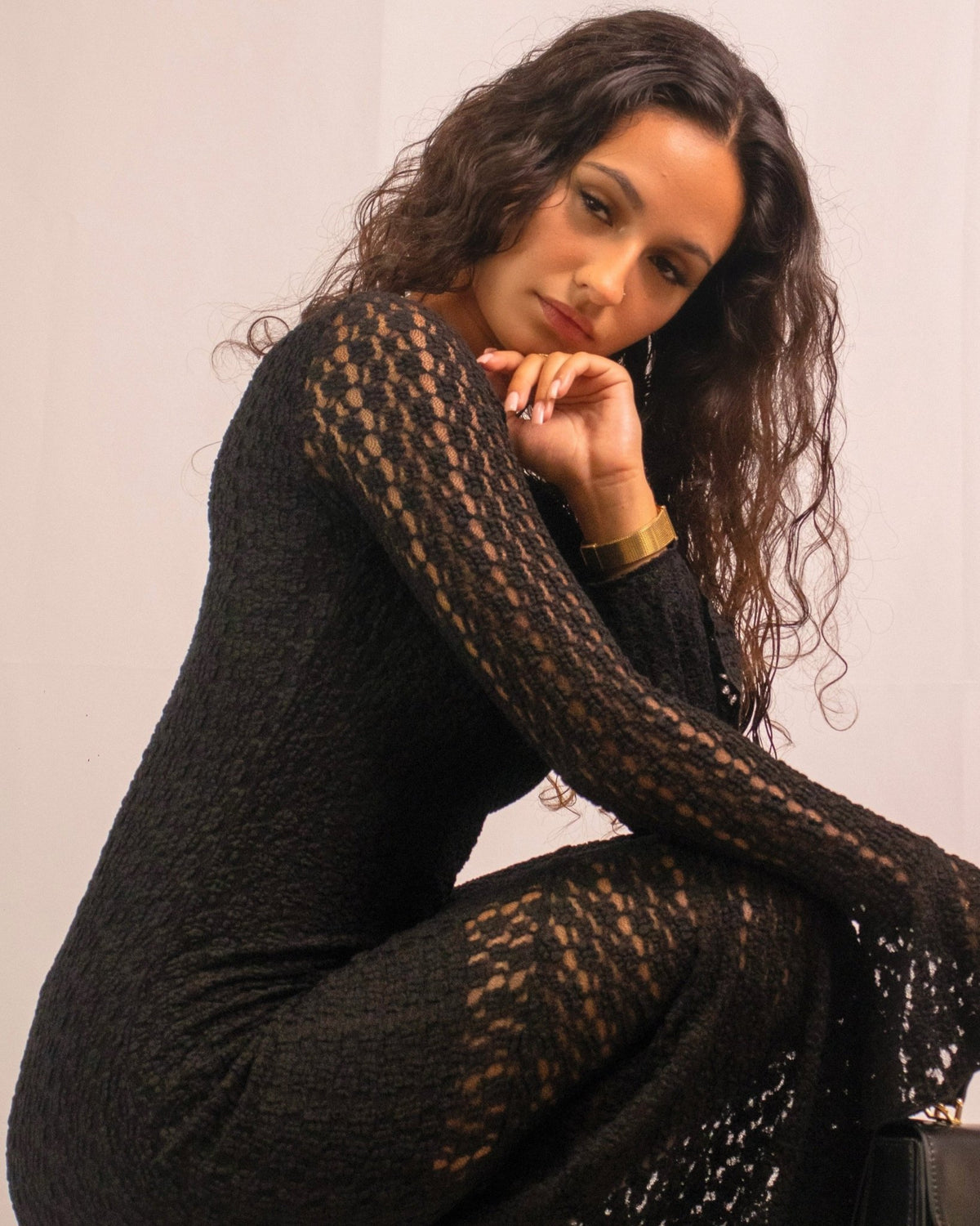 Vestido de renda preta com mangas compridas, padrão vazado e decote amplo