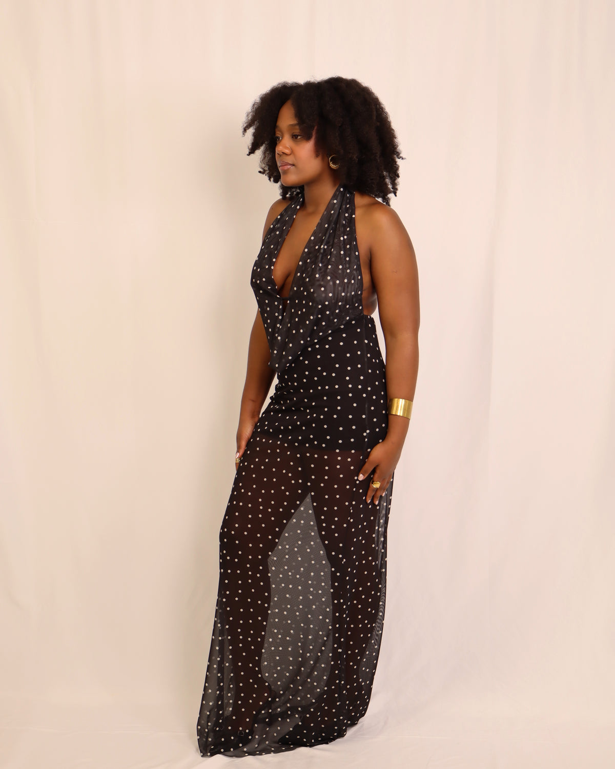 Vestido longo preto com padrão de pintas, decote halter, vista lateral.